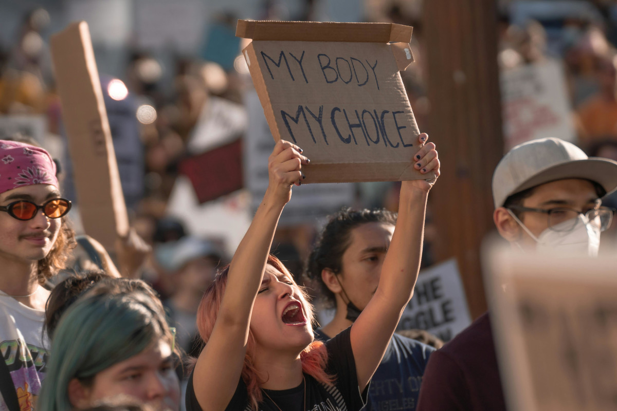 A protest crowd. Photo centers on a young woman holding a sign that says "MY BODY MY CHOICE"